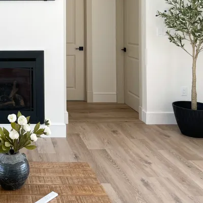 A home interior showcasing light wood plank flooring, a wooden coffee table, a fireplace, and a hallway with two modern beige interior doors featuring black hardware.
